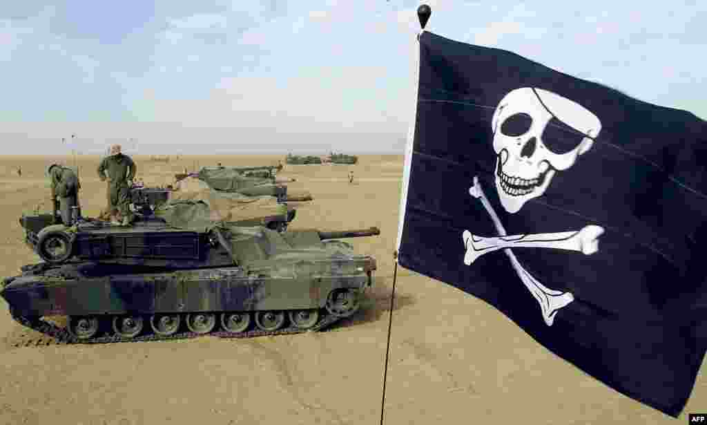 Pușcași marini rezerviști cu steagul lor Jolly Roger (steag de pirați) pe un tanc M1A1 Abrams la tabăra Grizzly din Kuweit, 16 februarie 2003. Tancurile Abrams au trecut prin mai multe versiuni, M1, M1A1 și M1A2, fiecare cu îmbunătățiri la armament, protecție și sistemele electronice. &nbsp;