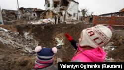 Діти стоять біля воронки, утвореної російським ракетним ударом під час атаки Росії на Україну, у місті Глеваха, під Києвом, 26 січня 2023 року. Фото ілюстративне 