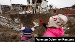 Деца стоят до кратер, оставен от руски ракетен удар край Киев, 26 януари 2023 г.