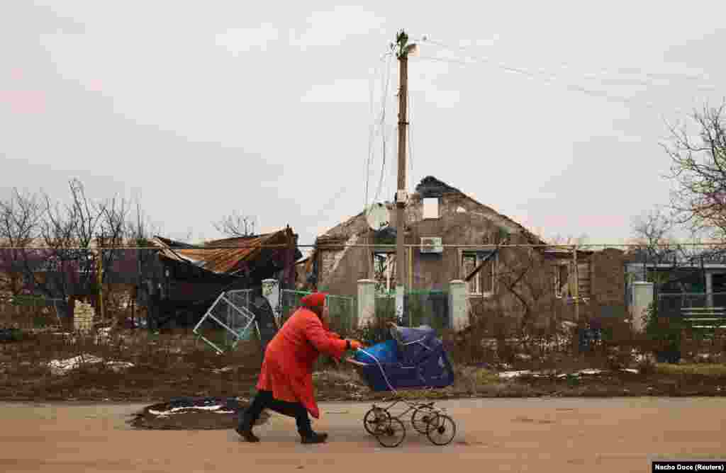 Anna, 78, transports food that volunteers gave her in the baby carriage of her late son in front of destroyed houses in a village near Kherson, Ukraine, on January 31 amid Russian&#39;s invasion.