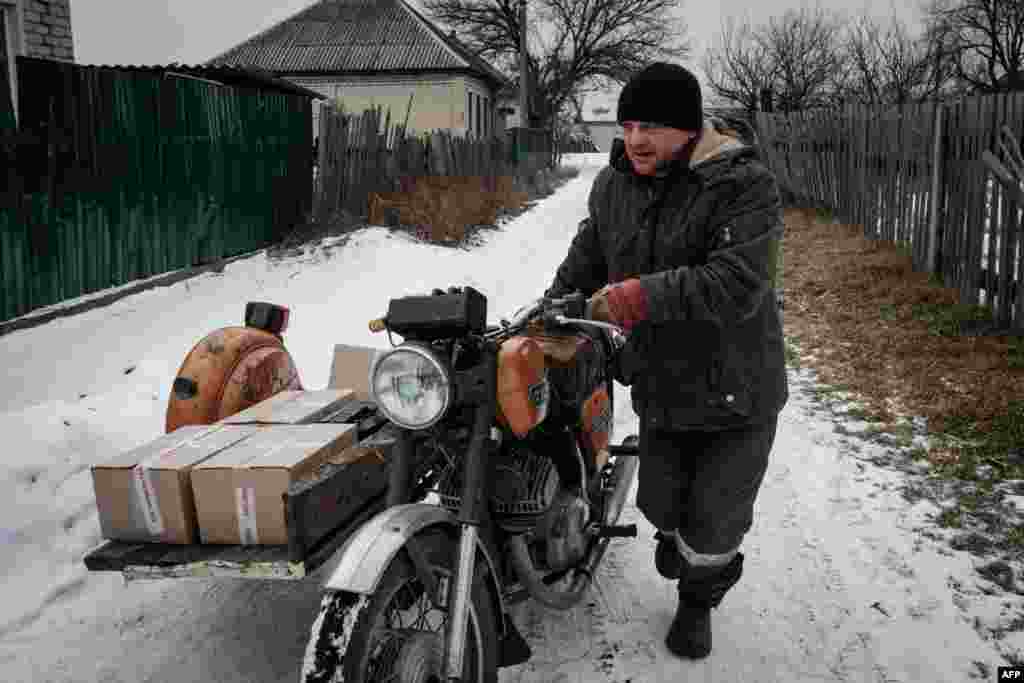 A 42 éves Ramisz tolja motorkerékpárját, amellyel élelmiszerrel töltött dobozokat szállít Viktoria Sipkónak
