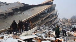 People look at rubble and damage following an earthquake in Hatay, Turkey