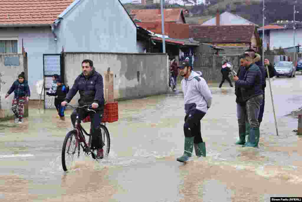 Një burrë duke ngarë biçikletën nëpër një rrugë të vërshuar, në Mitrovicën e Jugut.