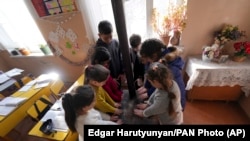 Nagorno-Karabakh - Schoolchildren warm themselves around a stove in the classroom in Stepanakert, December 15, 2022. 