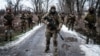 Українські військовослужбовці позують на дорозі, йдучи до своєї бази біля лінії фронту в Донецькій області, 4 лютого 2023 року