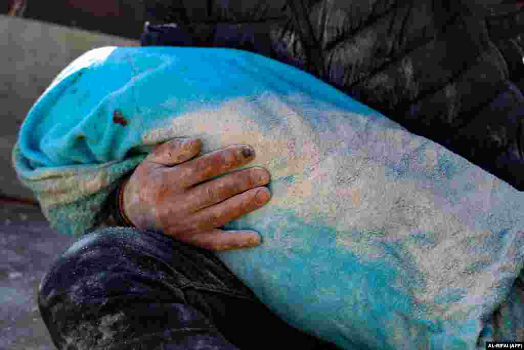Un bărbat ține în brațe cadavrul copilului său scos din dărâmături în orașul Harim, în provincia Idlib, nord-vest, controlată de rebeli ai Siriei, la granița cu Turcia, la 8 februarie 2023, la două zile după un cutremur mortal care a lovit Turcia și Siria.