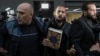 Andrew Tate (center) and his brother Tristan (right) are escorted by policemen as they leave theDirectorate for the Investigation of Organised Crime and Terrorism in Bucharest on January 26.