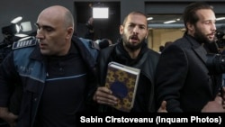 Andrew Tate (center) and his brother Tristan (right) are escorted by policemen as they leave theDirectorate for the Investigation of Organised Crime and Terrorism in Bucharest on January 26.