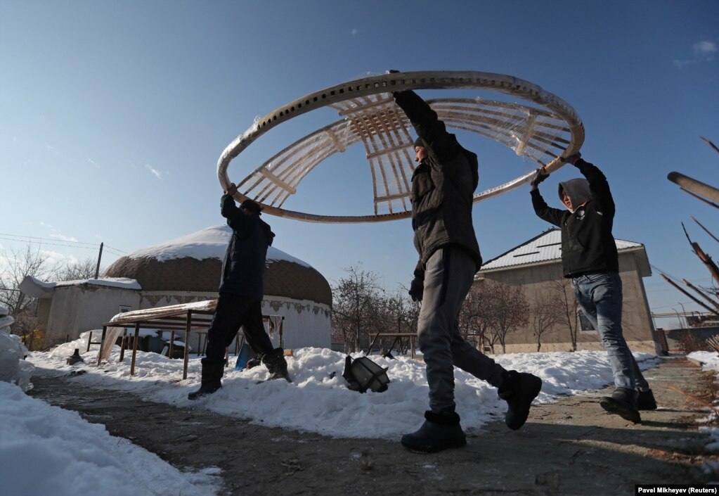 This February 1 photo shows Kazakh volunteers carrying a &quot;tunduk,&quot; the central portal of a yurt, towards a truck being filled with supplies for Ukraine. The men are preparing the aid shipment in the village of Qainazar, just east of Almaty.