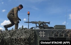 Një ushtar gjerman duke ecur mbi një tank të llojit Leopard, gjatë stërvitjeve të NATO-s, në jug të Gjermanisë, më 2017.