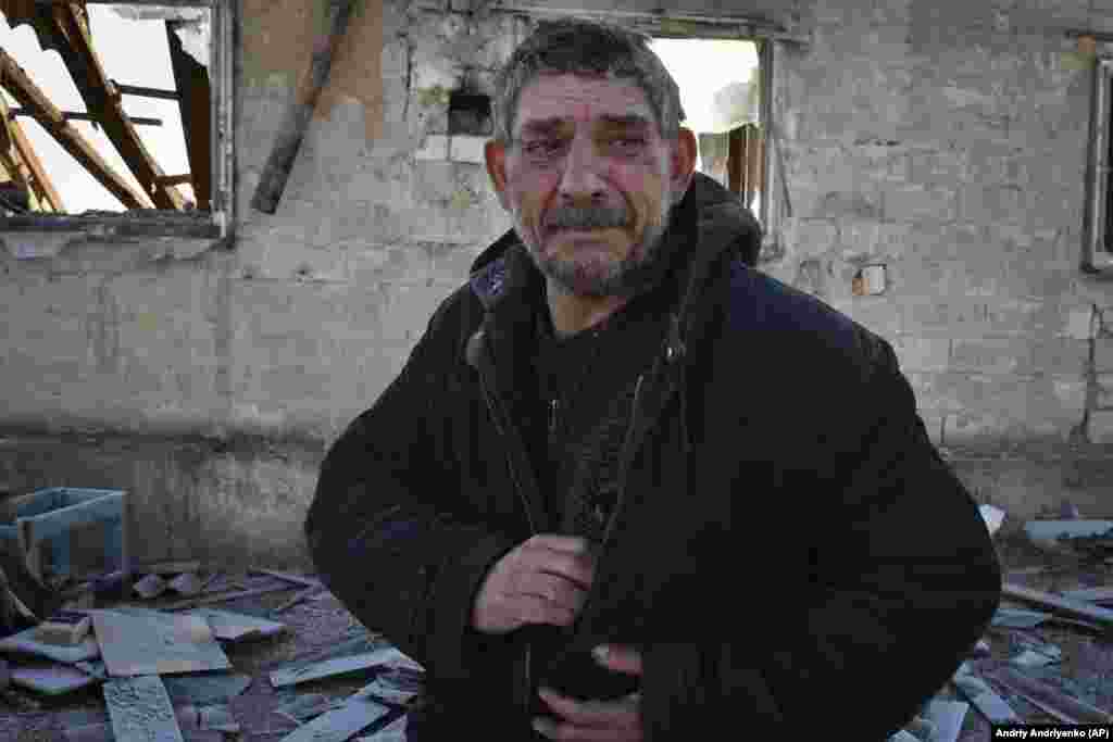 Rusiye raketası Zaporijjâda evlerini yoq etkende apayı vefat etken adam ağlay, 2023 senesi yanvarniñ 25-nden 26-na keçer gecesi.