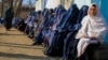 Afghans wait to receive food and coal distributed by an aid group in Kabul.