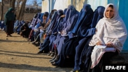 Afghans wait to receive food and coal distributed by an aid group in Kabul.