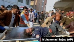  Рабочие и волонтеры несут раненого в результате взрыва смертника по прибытии в больницу в Пешаваре, 30 января 2023 г.