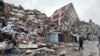 People stand in front of collapsed buildings following an earthquake in Kahramanmaras, Turkey, on February 6.