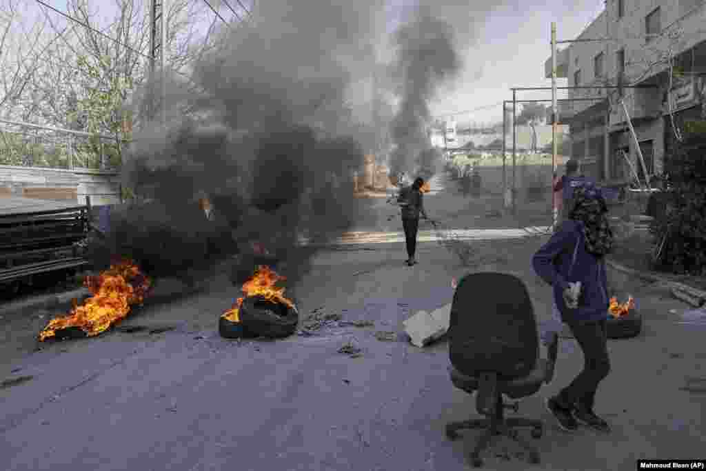 Demonstrues të maskuar palestinezë duke djegur goma, në protestë pas operacionit vdekjeprurës izraelit.