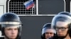 Задържан протестиращ развява руското знаме от вътрешността на полицейски автобус по време на неразрешен митинг с искане да независими и опозиционни кандидати да могат да се кандидатират на местните избори, Москва, 27 юли 2019 г. 