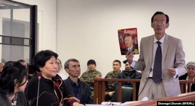 Акылжан Куантаев, младший брат и защитник подсудимой Жанны Есмурзаевой, показывает журнал с изображением Адольфа Гитлера на обложке, изъятый полицией при обыске дома подозреваемой. Актобе, 12 января 2023 года