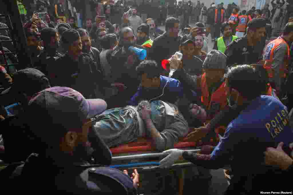 Men move an injured victim after a suicide blast at a mosque in Peshawar, Pakistan, that killed at least 100 people on January 30.