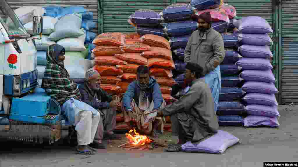 Muncitori așteptând să li se dea de lucru într-o dimineață friguroasă la piața de grâne angro din Karaci, Pakistan, 23 ianuarie 2023.