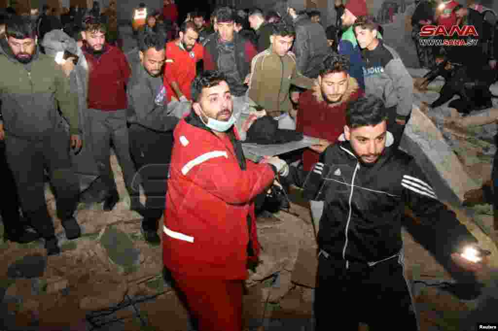 Спасувачите носат лице на носилки на местото на урната зграда, по земјотресот, во Хама, Сирија, во овој материјал објавен од САНА на 6 февруари 2023 година.