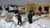 Children at a camp for internally displaced people (IDPs) shovel snow near their tents in the Nahr-e-Shahi district of Balkh Province, near Mazar-i-Sharif, on January 17. Kabul and several other provinces have seen record-low temperatures since January 10, with Ghor in the central region reaching the lowest reading of -33 Celsius (-27 Fahrenheit).<br />
<br />
&nbsp;