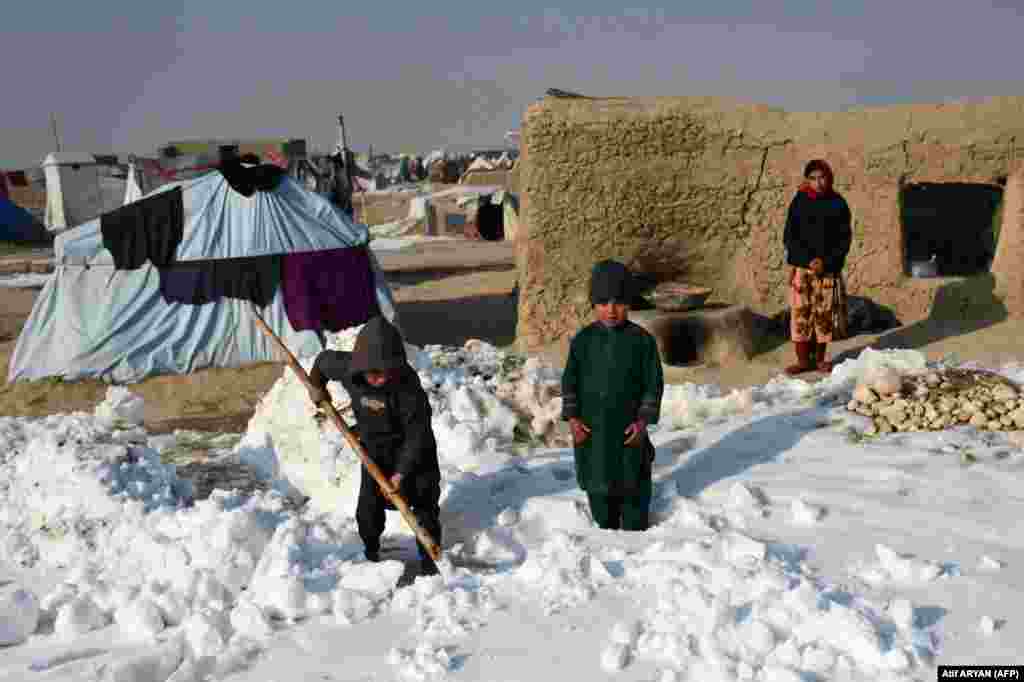 Fëmijët në një kamp për të zhvendosurit brenda vendit (PZHBV) shihen duke hequr borën pranë tendave të tyre në distriktin Nahr-e-Shahi të provincës Balkh, afër Mazar-i-Sharif, më 17 janar. Në Kabul dhe disa provinca të tjera janë shënuar temperatura rekord të ulëta prej minus 33 gradë celsius, që nga 10 janari. &nbsp;