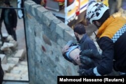 Egy mentő egy sérült gyermeket tart a karjában a lázadók által uralt Azazban, Szíriában 2023. február 6-án