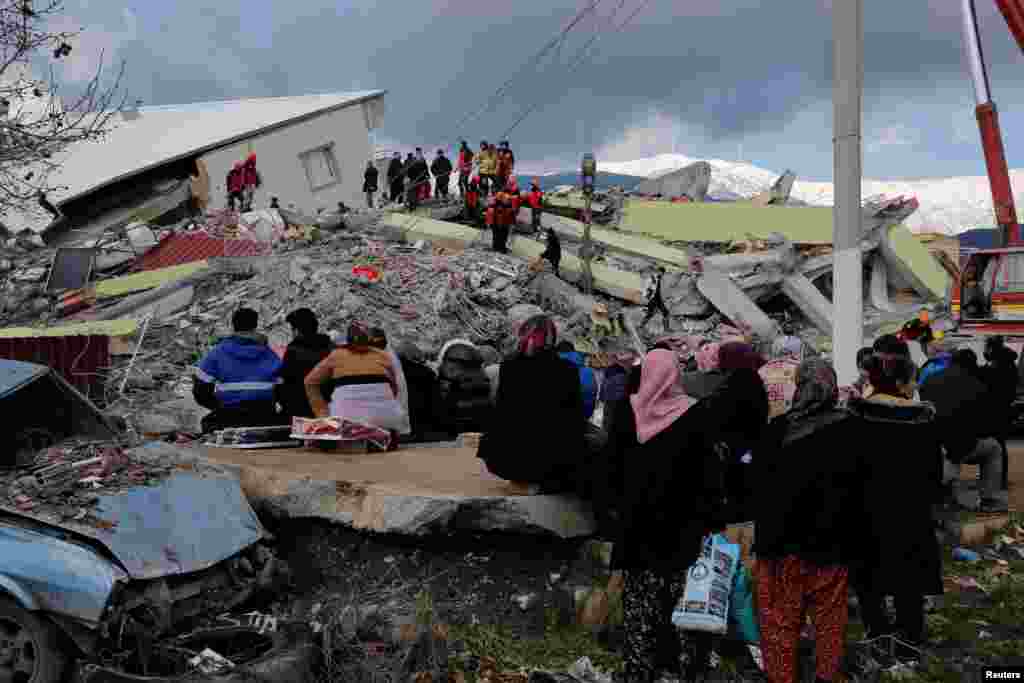 Oamenii stau în fața unei clădiri prăbușite, în urma unui cutremur din Gaziantep, Turcia, 7 februarie 2023. REUTERS/Dilara Senkaya