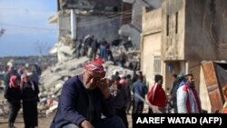 Сириец плачет, сидя на обломках обрушившегося здания в удерживаемом повстанцами городе Джиндайрис 7 февраля 2023 года после смертельного землетрясения. 