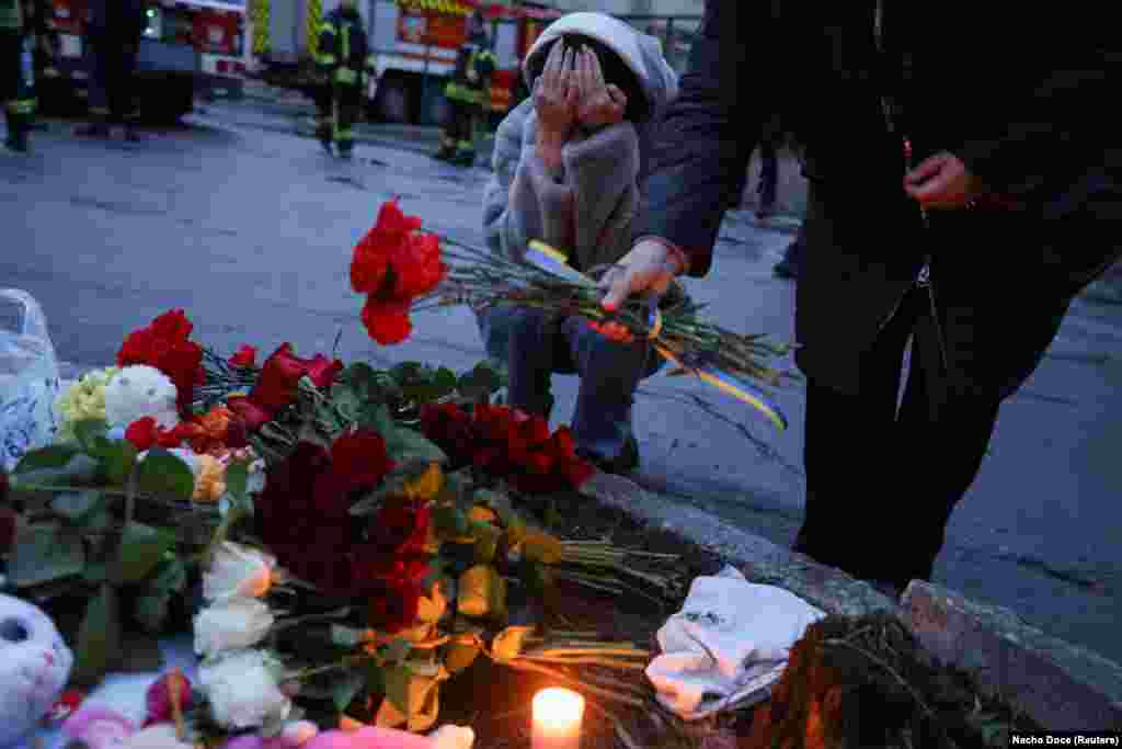 A woman reacts as she lays flowers near the site of a deadly helicopter crash in the town of Brovary, outside Kyiv.