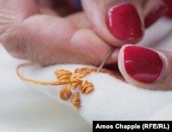 O croitoreasă brodează un model floral pe o ie în atelierul Andei Mănescu