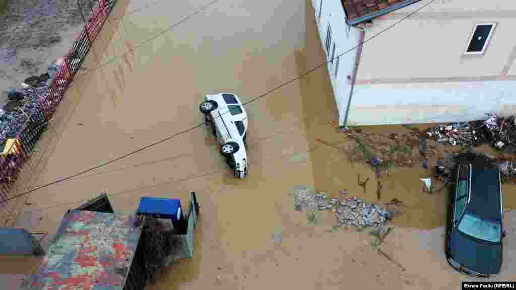 Një veturë e përmbysur pas vërshimeve në një rrugë , në Skenderaj.