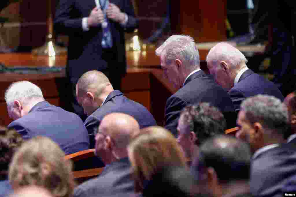 В това време в залата в Конгреса участниците в Националната молитвена закуска са свели глави по време на молитва. Вдясно е президентът Байдън, а до него е председателят на Камарата на представителите, републиканецът Кевин Маккарти.