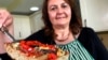 Тицијана ди Костанцо, ко-основачка на Хоризон инсектс, во нејзината кујна во Лондон, покажува парче пица чие тесто е направено од прав од мелени штурци