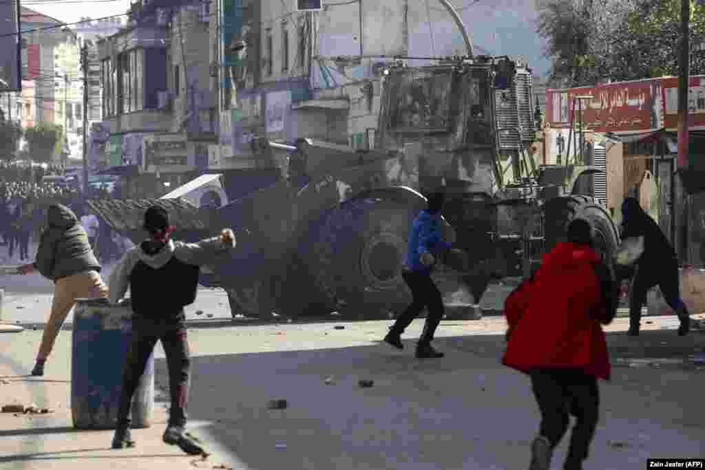 Palestinezët duke hedhur gurë ndaj një buldozeri të ushtrisë izraelite, gjatë konftrontimeve në Bregun Perëndimor.