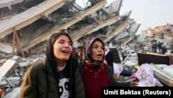 Люди плачут на месте разрушенного землетрясением дома. Хатай, Турция, 7 февраля 2023 года