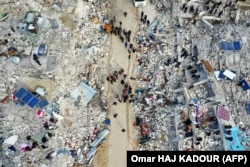 Жители, ищущие погибших и выживших среди обломков разрушенных зданий в деревне Бесния недалеко от города Харим, в удерживаемой повстанцами северо-западной сирийской провинции Идлиб на границе с Турцией. 6 февраля 2023 года.
