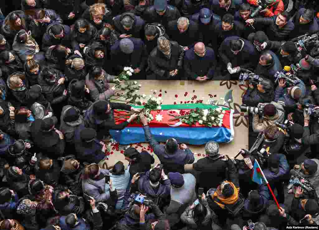 People gather around the coffin of Orkhan Askerov -- a security guard at the Azerbaijani Embassy in Iran who was shot dead by a gunman in a recent attack -- during a procession prior to his funeral in Baku on January 30.&nbsp;