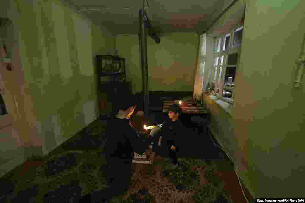 Two boys warm themselves next to a stove on January 18.&nbsp;Authorities also ordered schools to be closed due to the gas and electricity shortage. &nbsp;