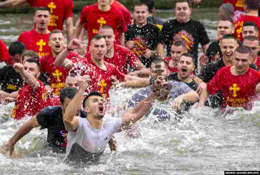 Kristijan Nineski, 26, catches the cross that was thrown in the Vardar River by the head of the Macedonian Orthodox Church, Archbishop Stefan, during Epiphany day celebrations in Skopje, North Macedonia.