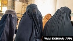 Afghan burqa-clad women stand in line to receive food aid from an NGO at a gymnasium in Kabul on January 17.