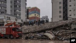  Хора и спешни екипи търсят хора в руините на разрушена постройка в Газиантеп, Турция, понеделник, 6 февруари 2023 година 