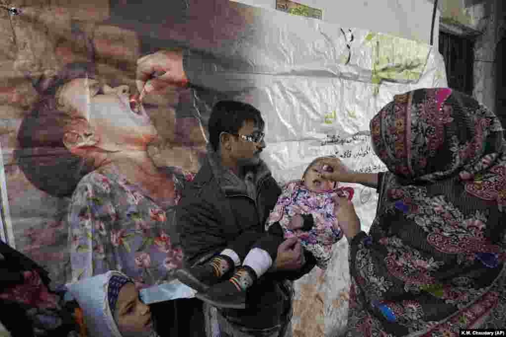 Një punonjëse shëndetësore duke e vaksinuar një fëmijë kundër poliomielitit në Lahore, Pakistan.