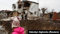 Дитина біля воронки, яка залишилася внаслідок російського ракетного удару у Глевасі на Київщині, 26 січня 2023 року