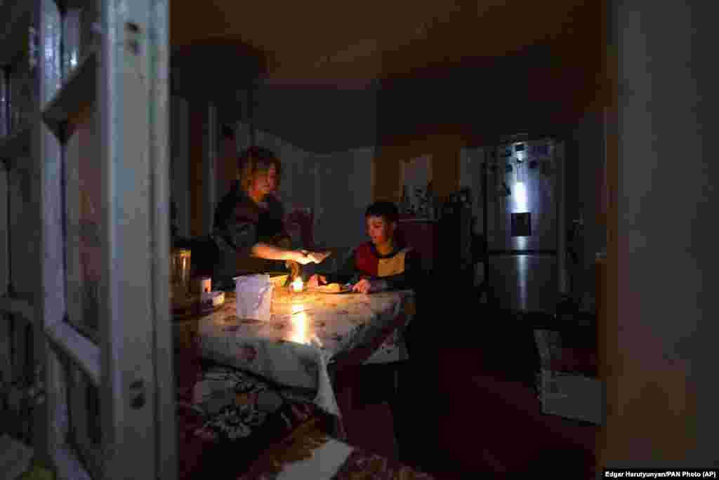 A woman and her son have dinner by candlelight at their home in Stepanakert. &nbsp;
