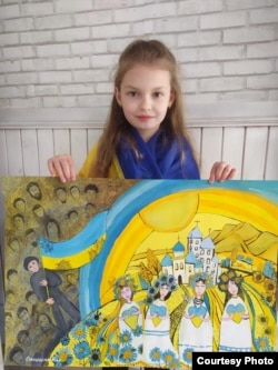 Nika holding one of her paintings, reflecting the 7-year-old's homesickness and the patriotic themes that dominate much of her work since picking up the paintbrush again in Bulgaria.