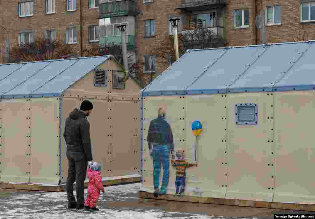 Another mural -- that of a man and a young child with a balloon -- catches the eye of a man and a young child on the wall of a &quot;points of invincibility&quot; center in Bucha.