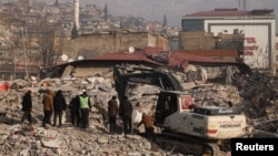 Турција. 12 февруари 2023 година - Луѓе стојат меѓу урнатините додека продолжуваат операциите за пребарување и спасување, како последица на смртоносниот земјотрес во Кахраманмарас. 