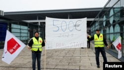 Sztrájkoló dolgozók a Berlin-Brandenburg repülőtér épülete előtt 2023. január 25-én